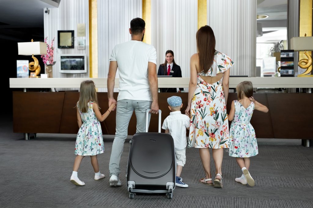 Family of five enters to the hotel lobby to check in at the reception for vacation