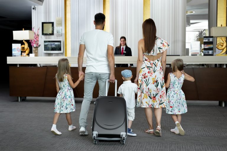 Family of five enters to the hotel lobby to check in at the reception for vacation