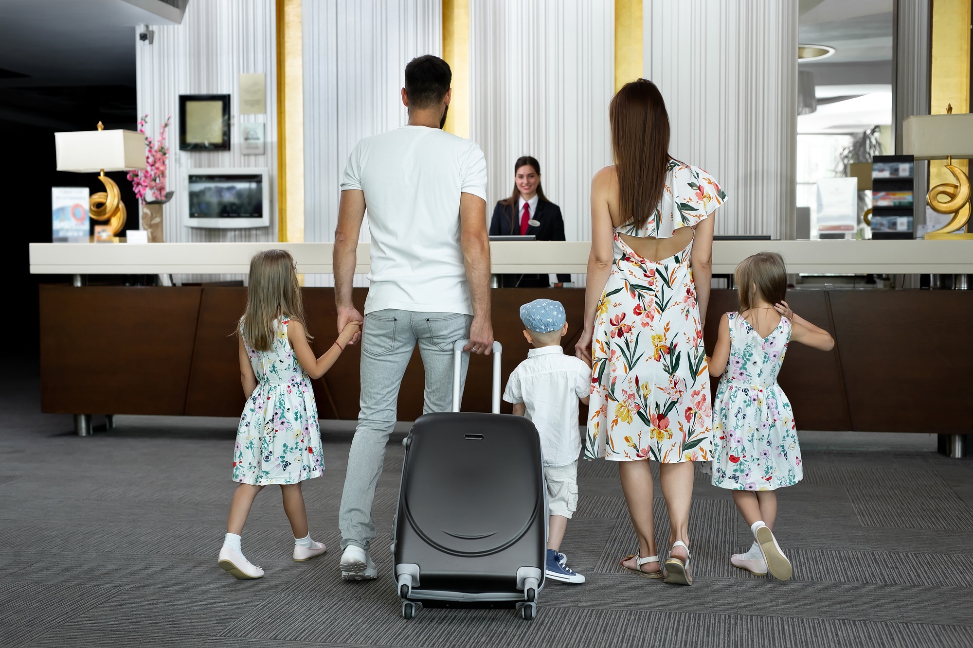 Family of five enters to the hotel lobby to check in at the reception for vacation